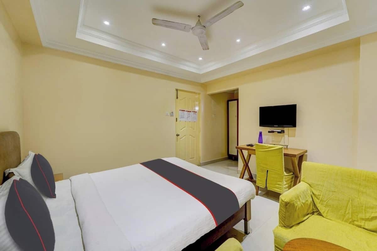 A hotel room with a bed, a desk, a chair, and a television.
