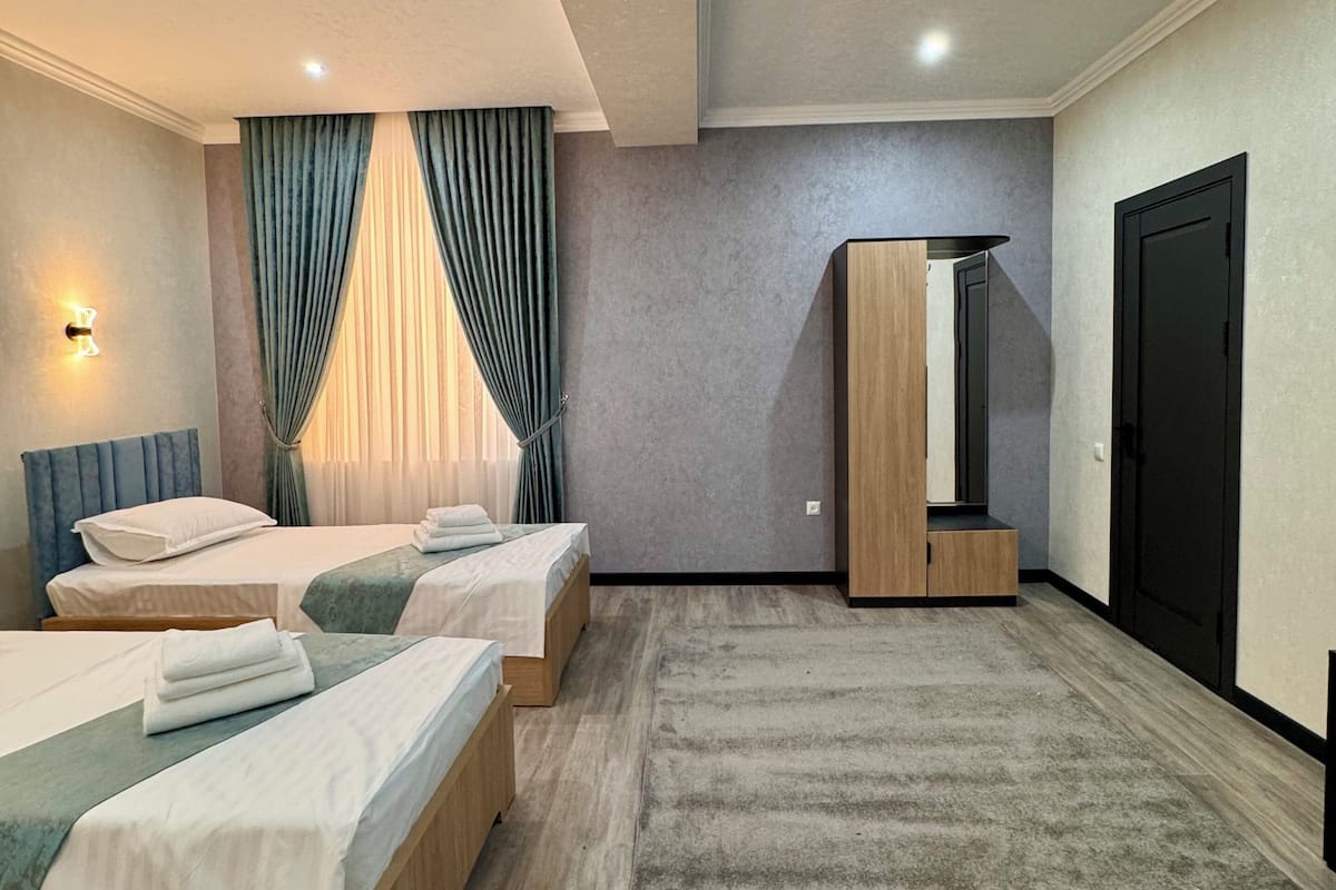 A modern hotel room with two beds, a large mirror, a wardrobe, and a carpeted floor.