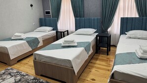 A hotel room with three single beds, a small table, and a TV. - Mehran (Fergana)