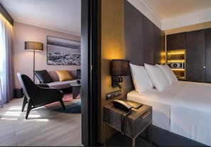 Una camera d'albergo con un letto, un comodino, una lampada e un divano con cuscini.