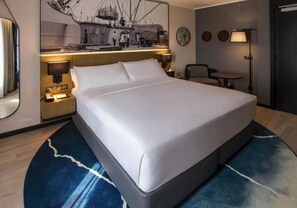 A hotel room with a large bed, bedside lamps, a small table, and a wall-mounted artwork. - K Hotels (Douala)