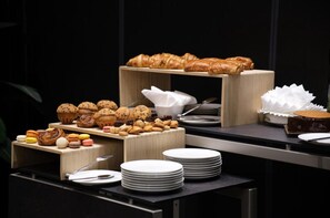 Un buffet con diverse preparazioni da forno, tra cui croissant, muffin, biscotti e macarons.