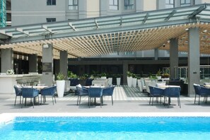 A poolside area with outdoor seating and a covered patio. - K Hotels (Douala)