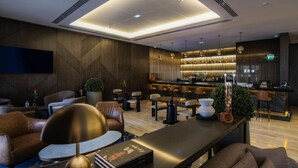 A modern lounge area with leather sofas, a long table, and a bar with a sleek design. - K Hotels (Douala)
