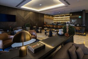 Een moderne lounge met lederen banken, een lange tafel en een bar met strak design.