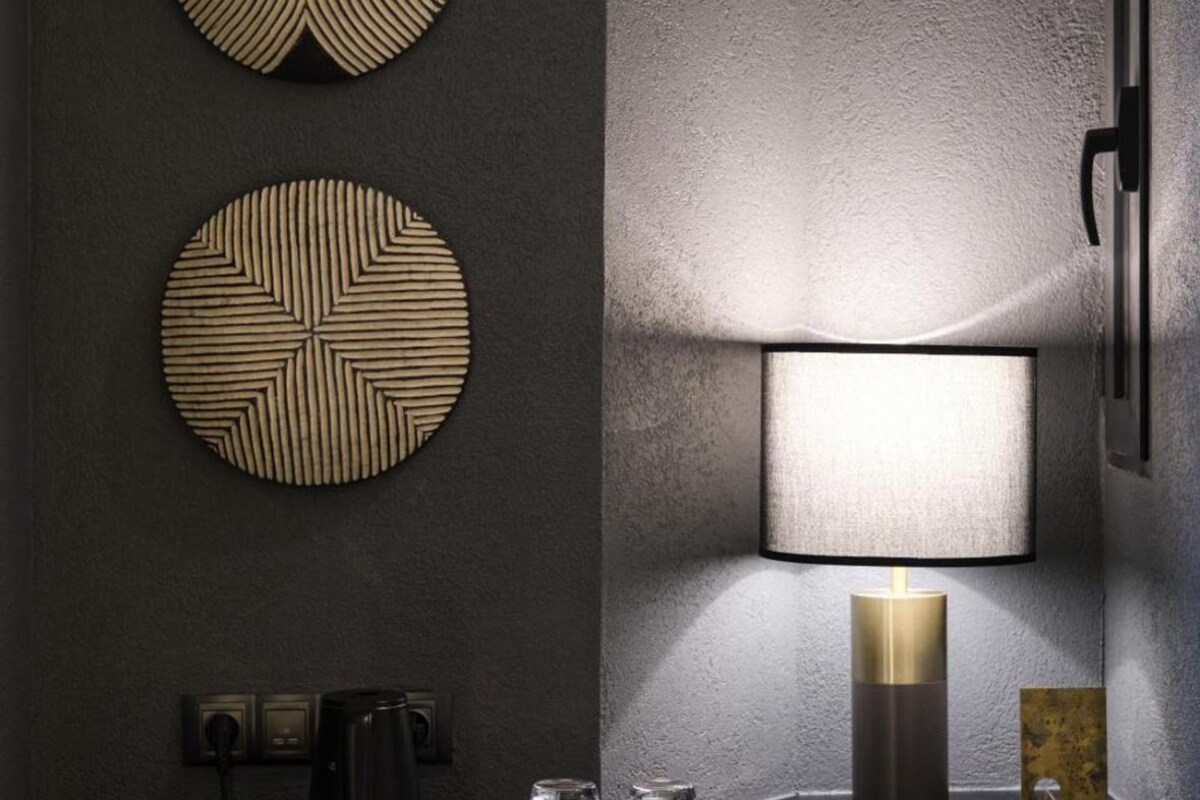 A modern bathroom with a round mirror, a wall-mounted lamp, and a coffee maker.