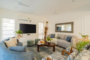 A living room with a sofa, a coffee table, a TV, and a mirror. - Elivaas Paraíso - Villa Goa (Siolim)