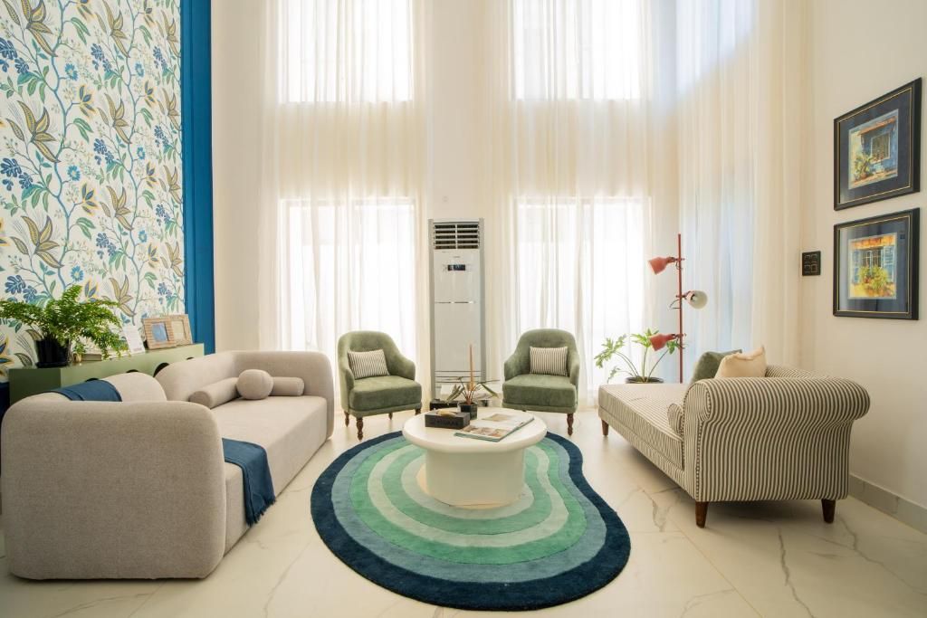 Ein Wohnzimmer mit einer Couch, Sesseln, einem Couchtisch und einem gestreiften Sofa.