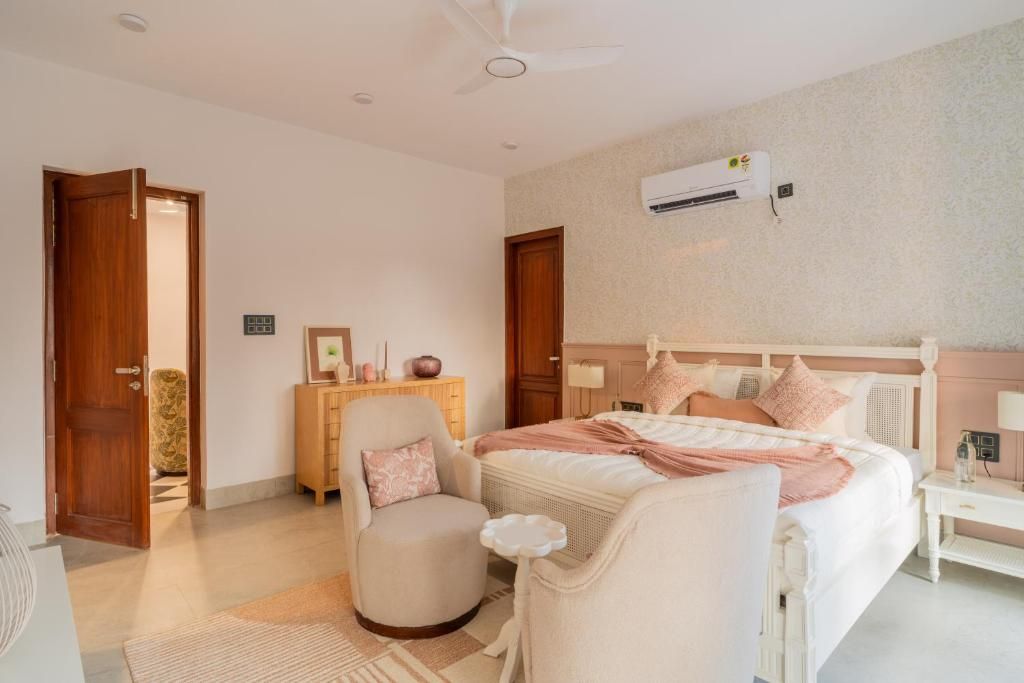 Un dormitorio con cama, una silla, mesita de noche, armario y aire acondicionado.