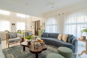 A living room with a sofa, chairs, a coffee table, and a dining area with a table and chairs. - Elivaas Paraíso - Villa Goa (Siolim)