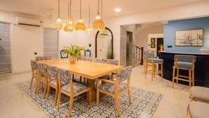 A dining area with a wooden table and chairs, hanging lights, and a patterned rug. - Elivaas Paraíso - Villa Goa (Siolim)
