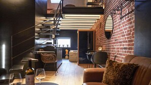 A modern interior with a staircase, a dining area with a table and chairs, and a brick wall. - Hôtel Oniro Tournai - Luxury Rooms & Wellnss Suits (Tournai)