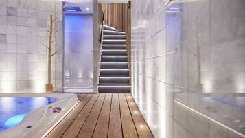 A modern spa area with a wooden floor, a hot tub, and a staircase leading to a higher level.