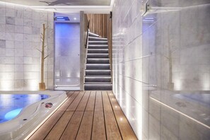 A modern spa area with a wooden floor, a hot tub, and a staircase leading to a higher level. - Hôtel Oniro Tournai - Luxury Rooms & Wellnss Suits (Tournai)