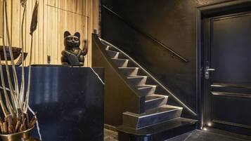 Um interior moderno com uma escada preta, uma mesa de recepção e uma estátua decorativa de gato.