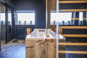 A modern room with a foosball table, large windows with potted plants, and a marble floor.