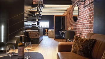 A modern interior with a staircase, a dining area with a table and chairs, and a brick wall.