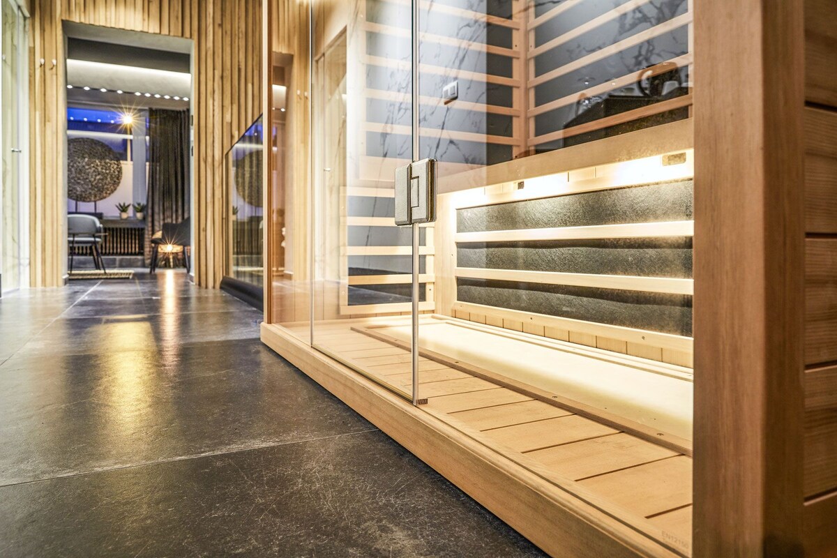 A sauna area with wooden benches and a glass door, a polished floor, and a modern interior design.