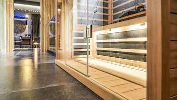 A sauna area with wooden benches and a glass door, a polished floor, and a modern interior design.