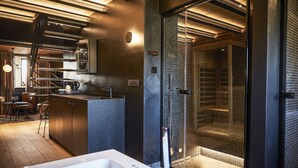 A modern bathroom with a large bathtub, a glass shower enclosure, and a kitchen area with a bar. - Hôtel Oniro Tournai - Luxury Rooms & Wellnss Suits (Tournai)