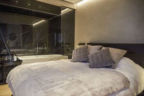 A modern bedroom with a large bed, a glass-enclosed bathtub, and a minimalist design. - Hôtel Oniro Tournai - Luxury Rooms & Wellnss Suits (Tournai)