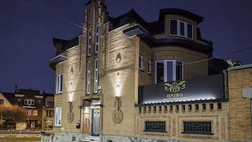 Rakennus, jonka yläpuolella on yöllä valaistu kyltti, jossa lukee: ”ONIRO WELLNESS ROOMS & SUITES”.
