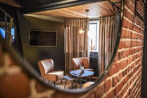 A cozy room with leather chairs, a small table, and a hanging light fixture. - Hôtel Oniro Tournai - Luxury Rooms & Wellnss Suits (Tournai)
