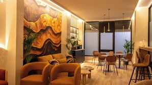 Een modern interieur met een zithoek, houten tafels en een groot abstract schilderij aan de muur.