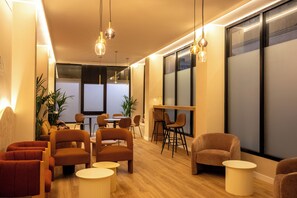 A modern interior with wooden flooring, multiple seating areas, and pendant lighting. - Casa Ollerias (Córdoba)