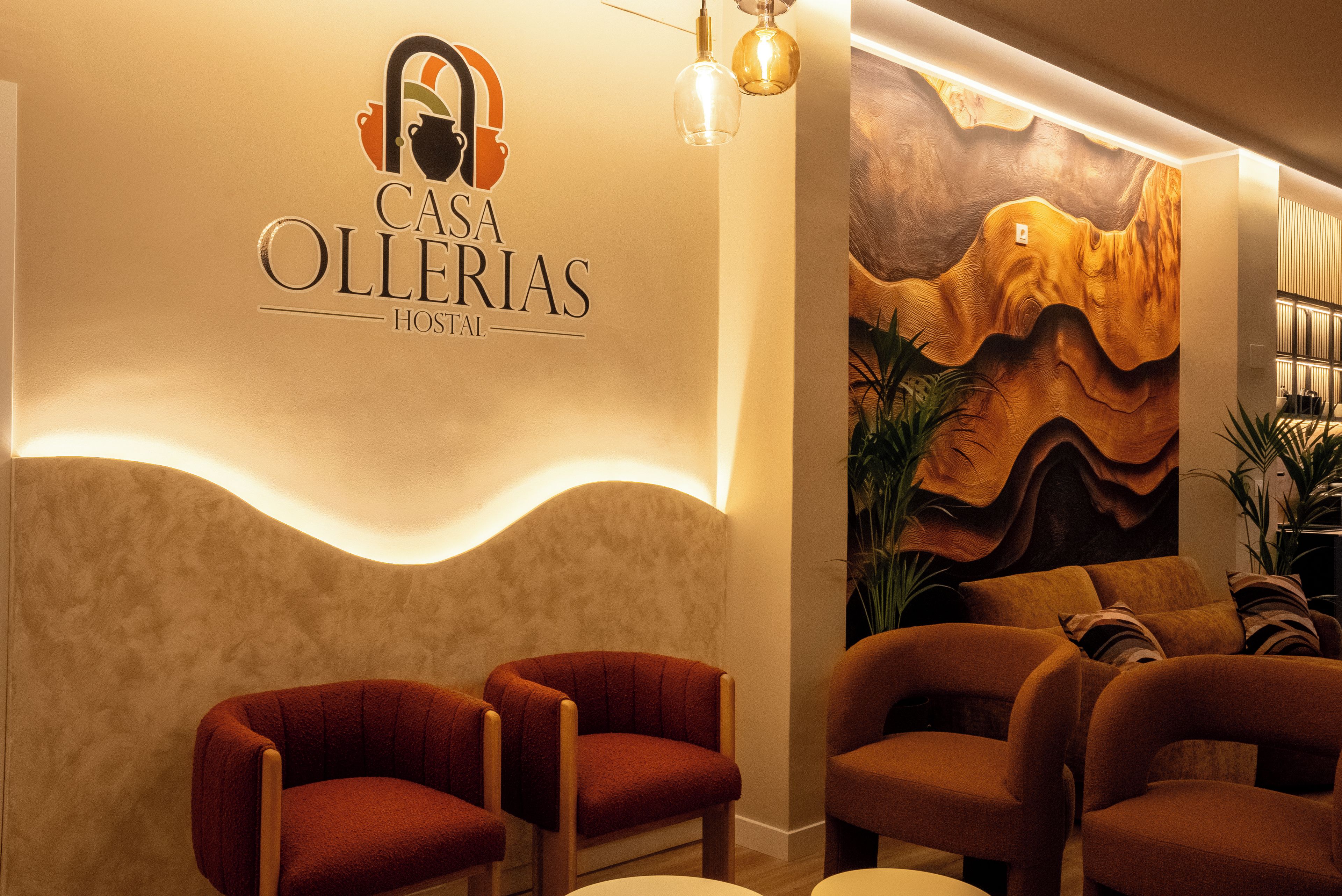 A hotel lobby with a modern design, featuring a logo on the wall, a seating area with chairs, and a decorative wall mural.