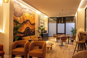 A modern interior with a seating area, wooden tables, and a large abstract painting on the wall. - Casa Ollerias (Córdoba)