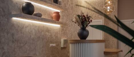 Una moderna zona de recepción con un mostrador de madera, un jarrón con flores y un sofá marrón.
