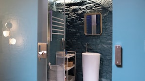 A bathroom with a stone wall, a white sink, a mirror, and a shelf with baskets. - Ad Calcem "lagodentro" (Terlizzi)