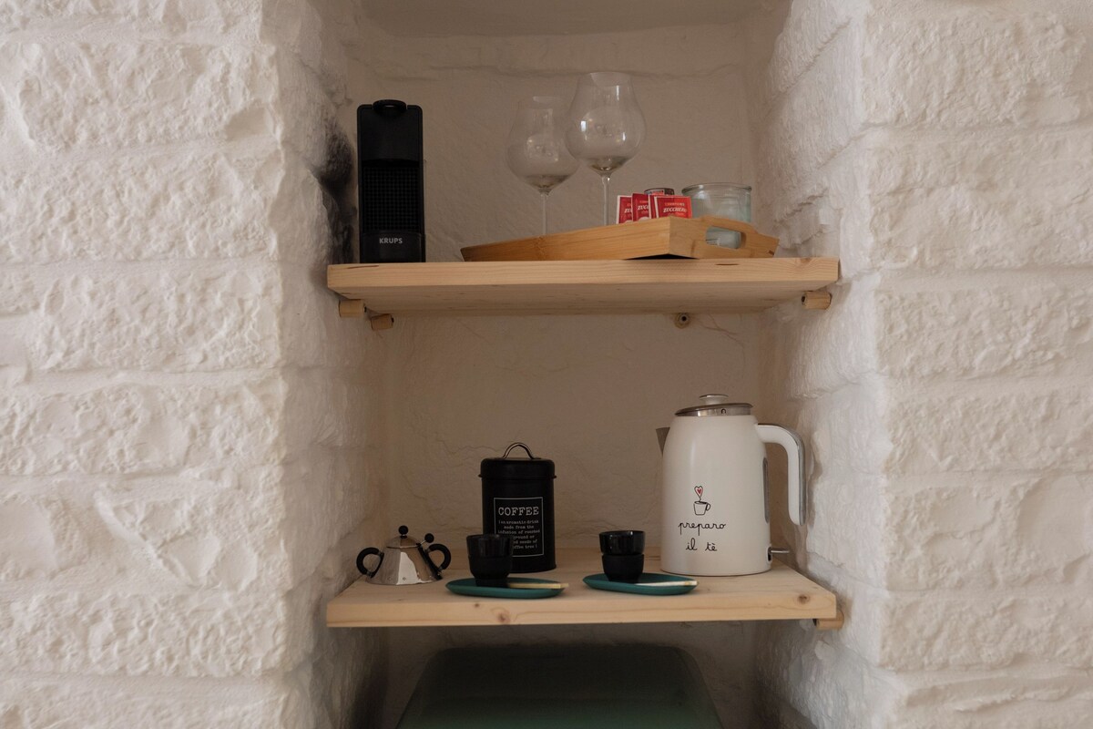 A small kitchenette with a coffee maker, a kettle, and a vintage-style refrigerator.