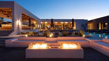 Un área de piscina moderna al aire libre con asientos integrados y una chimenea.
