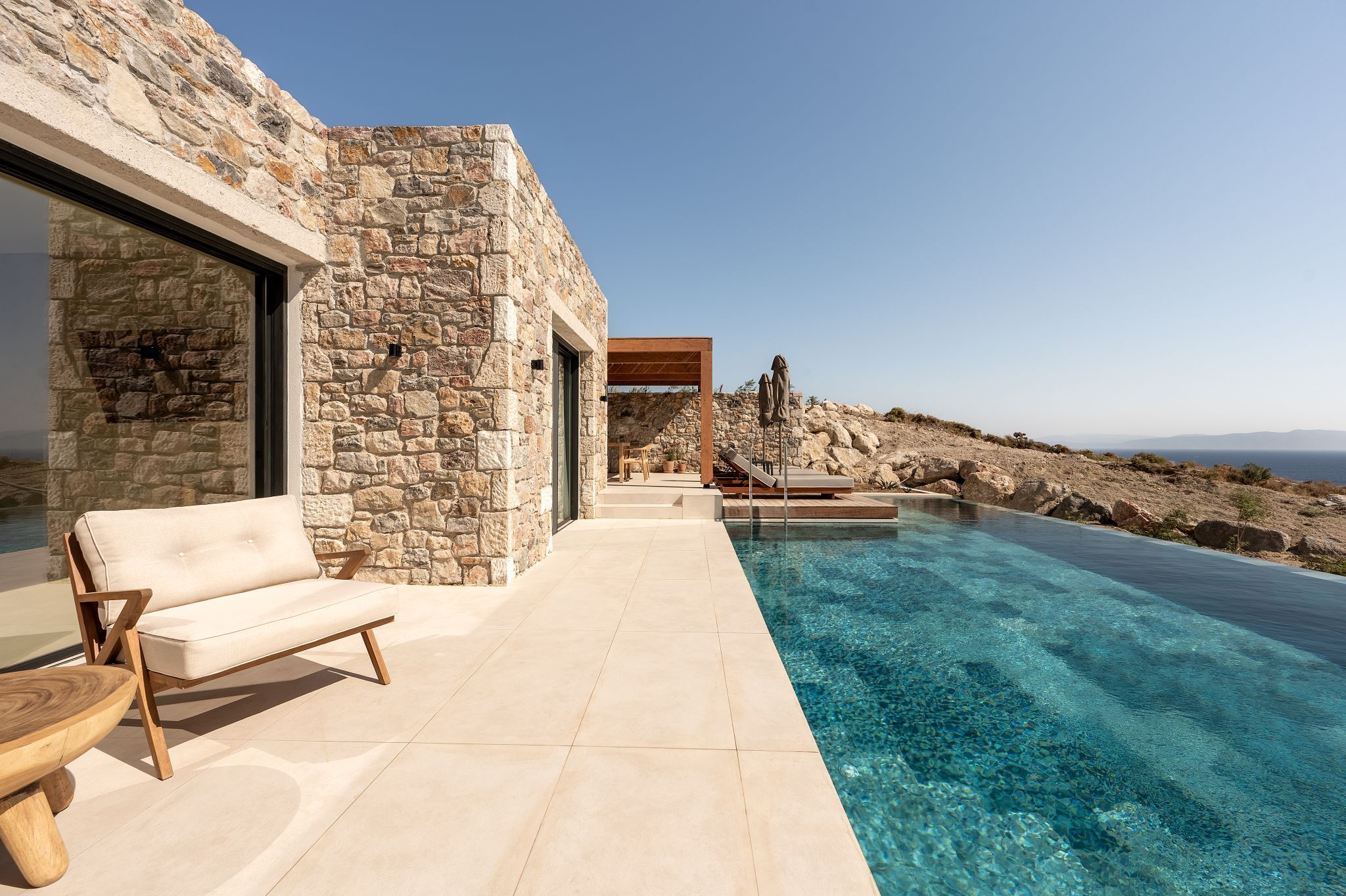 A stone building with a pool, a sofa, and a table.
