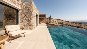 A stone building with a pool, a sofa, and a table. - Koia All-suite Wellbeing Resort (Kos)