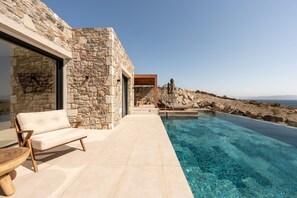 A stone building with a pool, a sofa, and a table. - Koia All-suite Wellbeing Resort (Kos)