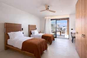 Ett hotellrum med två sängar, en takfläkt, ett stort fönster med utsikt och en garderob i trä.