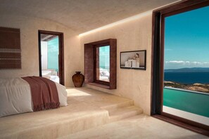 A bedroom with a bed, a large window, a vase, and a framed picture.