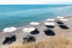 A beach with umbrellas and lounge chairs arranged for sunbathing.