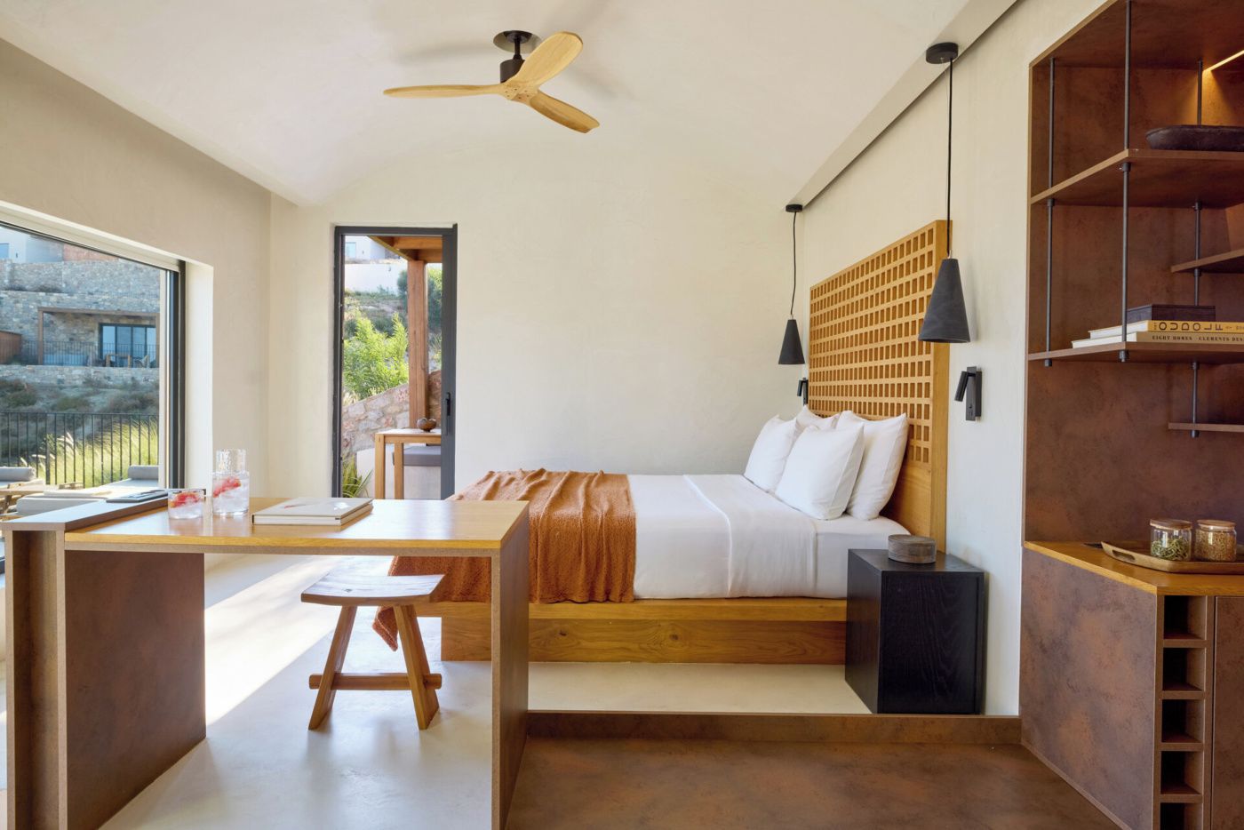A modern bedroom with a wooden bed, a desk, and a view of the outdoors.