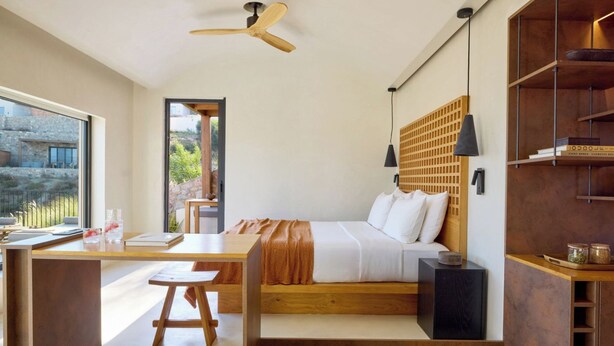 A modern bedroom with a wooden bed, a desk, and a view of the outdoors. - Koia All-suite Wellbeing Resort (Kos)