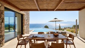 An outdoor dining area with a view of the sea, a pool, and a mountain range. - Koia All-suite Wellbeing Resort (Kos)