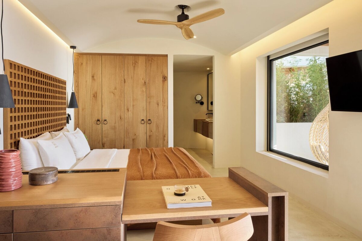 A modern room with a wooden dining table, a sofa, and a large window.