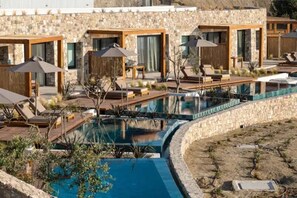A modern resort with a swimming pool, sun loungers, and wooden pergolas. - Koia All Suite Wellbeing Resort (Kos)
