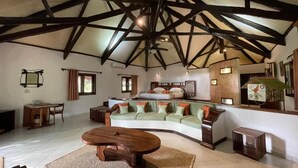 A spacious living area with a high ceiling, a curved sofa set, a wooden coffee table, and a small side table. - Ravintsara Wellness Hotel (Nosy Be)