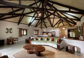 A spacious living area with a high ceiling, a curved sofa set, a wooden coffee table, and a small side table. - Ravintsara Wellness Hotel (Nosy Be)