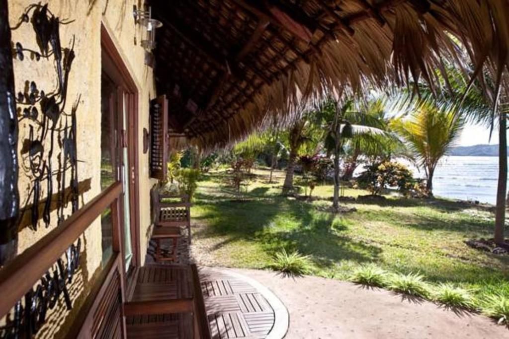 A covered outdoor area with a wooden deck, a thatched roof, and a view of a body of water.