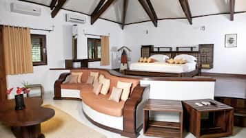 Une pièce chaleureuse avec un canapé incurvé, une petite table en bois, un lit avec une tête de lit en bois et une fenêtre avec des rideaux.